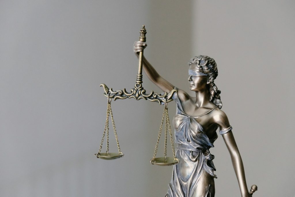 Justice, blindfolded, holds the scales (a statue).