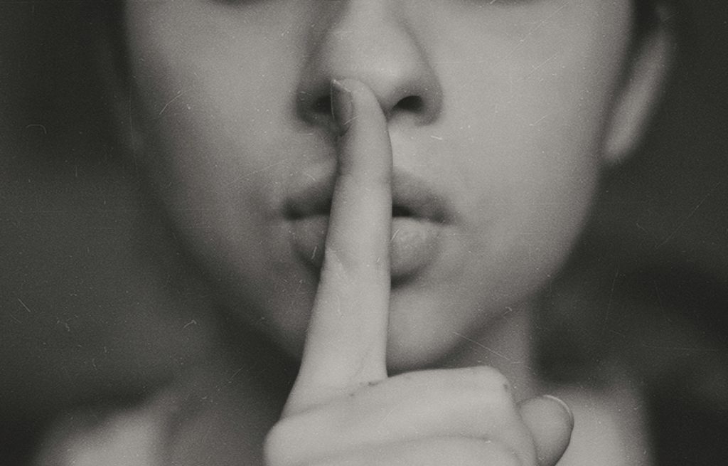 A person holds their finger up to their lips.